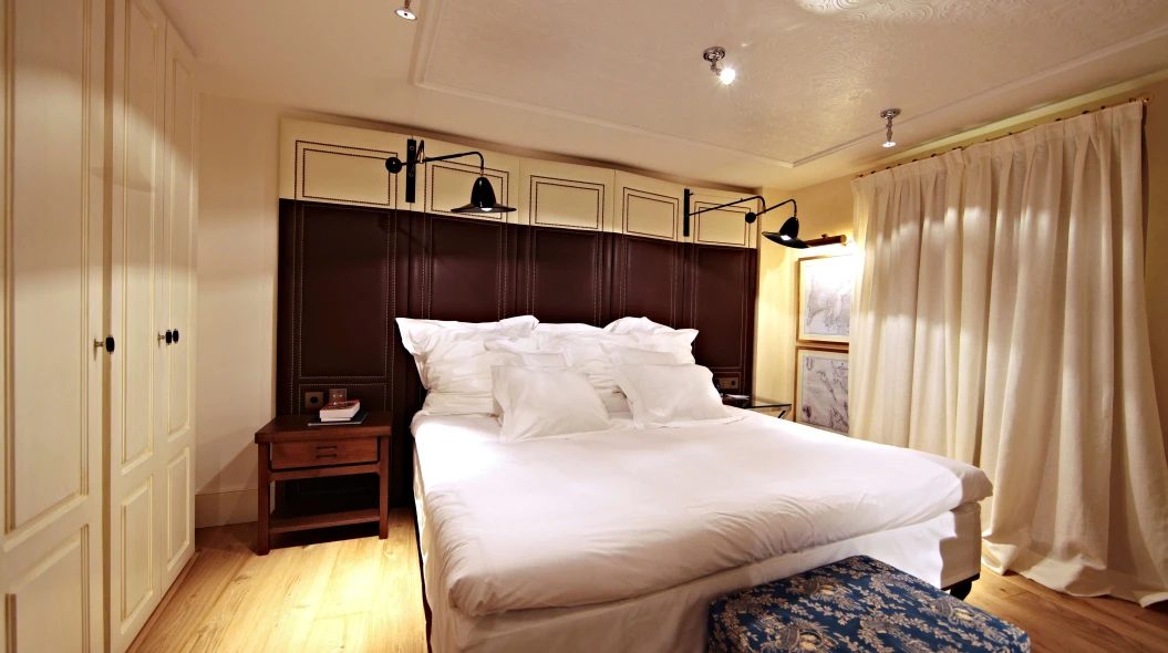 Cocoon room at Hotel Cort with a dark leather panelled headboard, wall-mounted reading lights, and cream wardrobe cabinetry