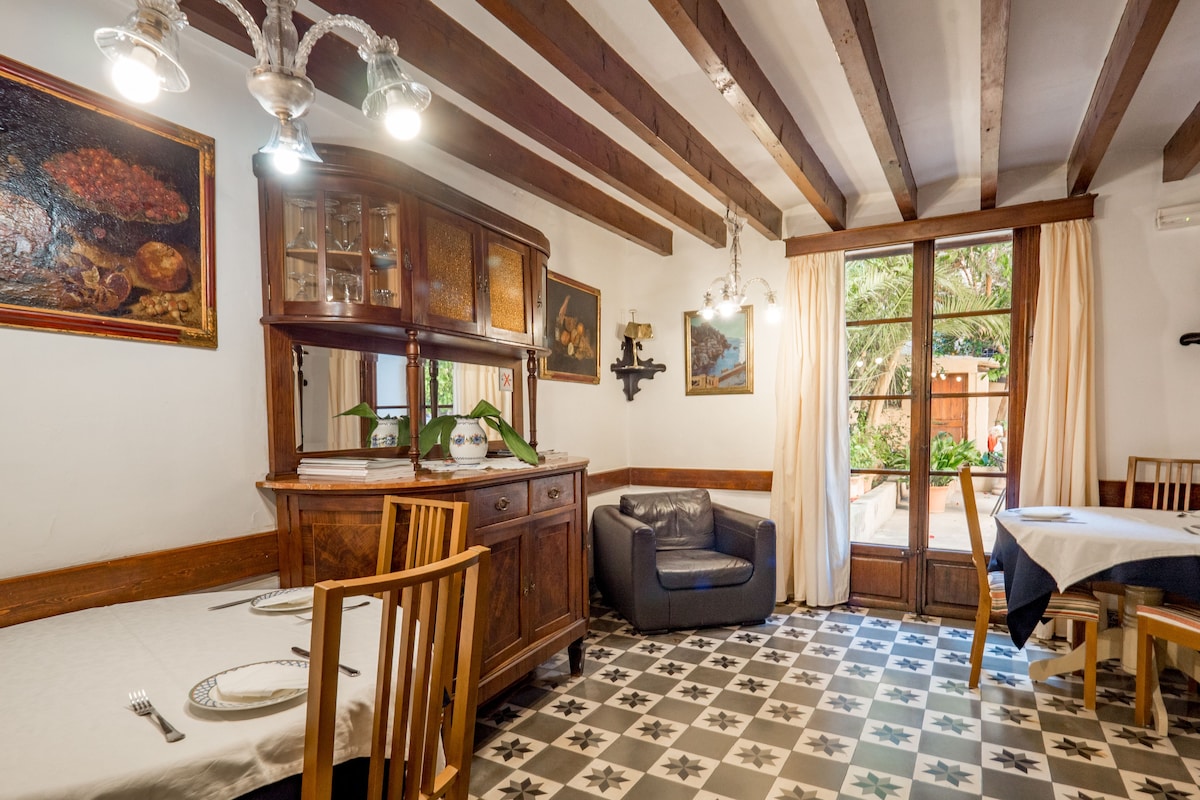 Breakfast room at Hotel Dalt Murada with hydraulic-tiled floors and tall doors opening onto a planted courtyard