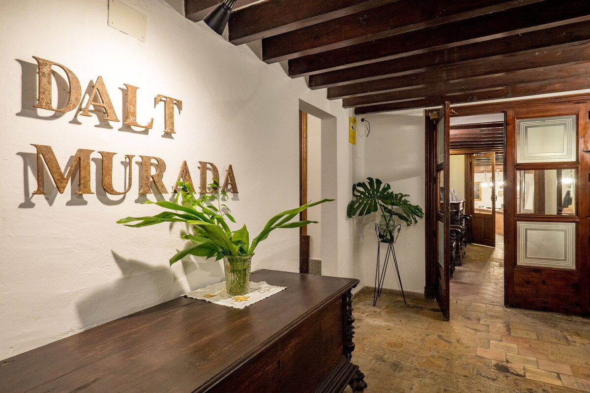 Entrance hall at Hotel Dalt Murada with the hotel's name in metal letters above an antique wooden chest and beamed ceiling