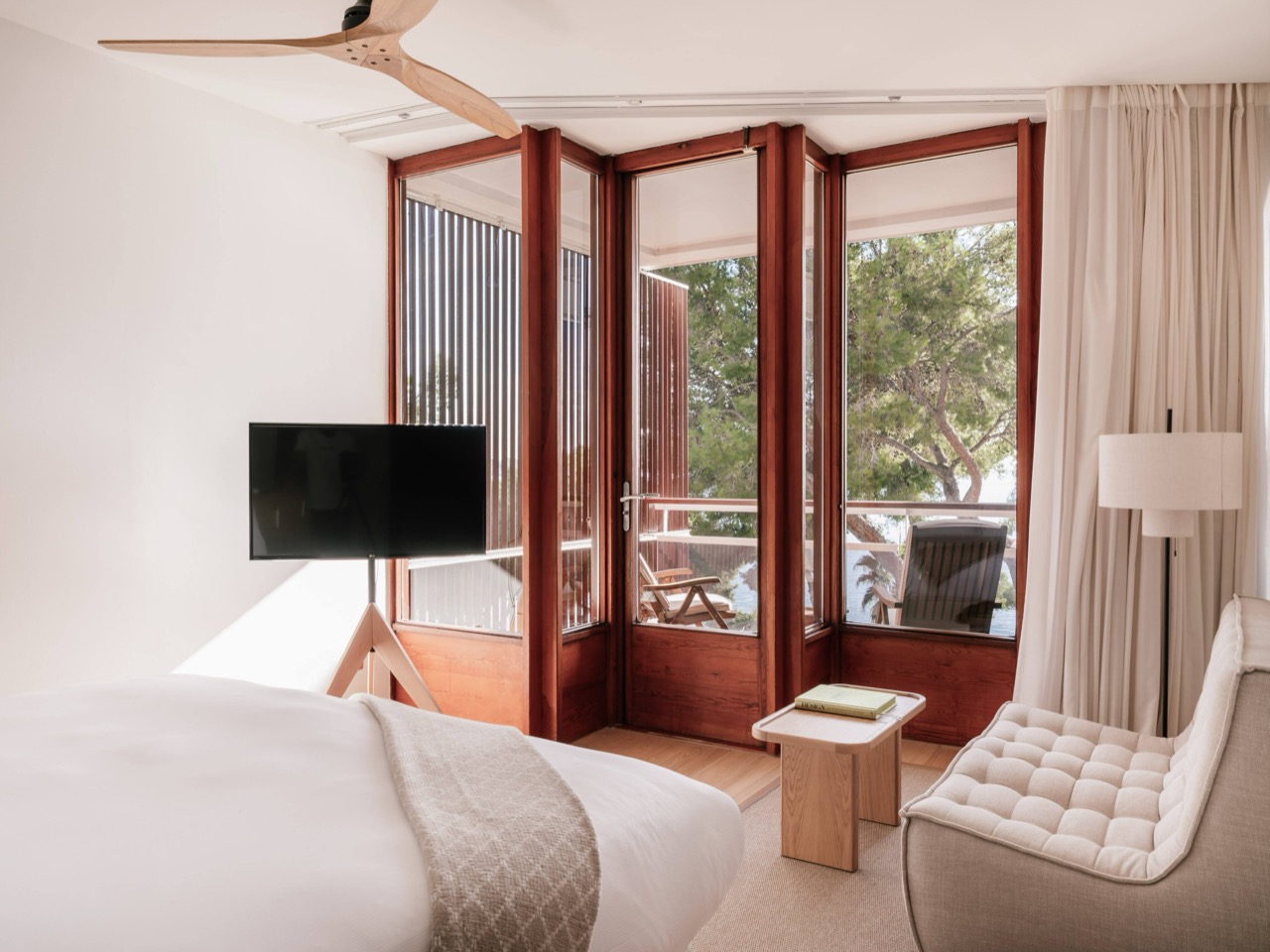 Guest room with wood framed balcony doors opening to pine trees