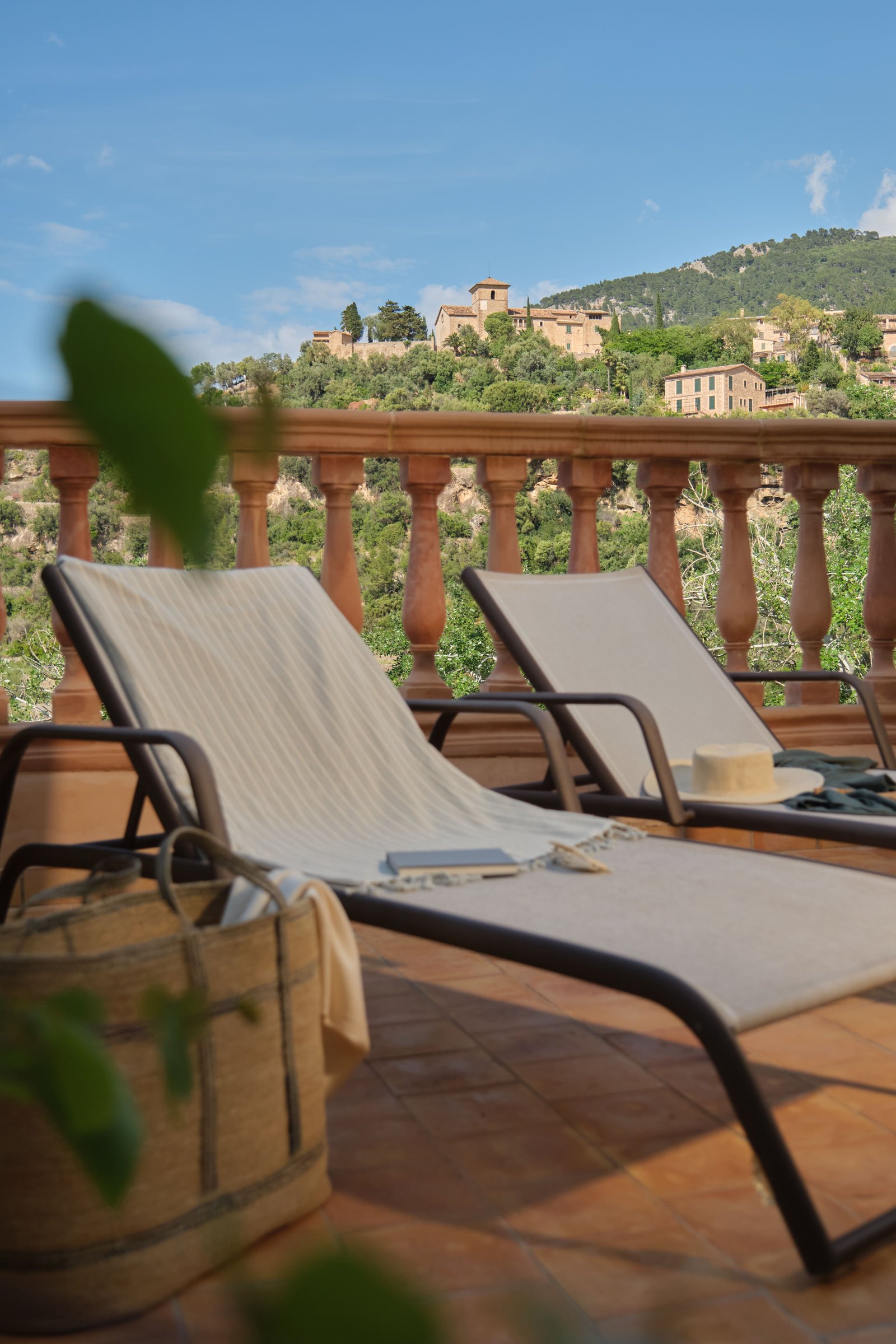 Terrace sunloungers with books and sunhats, looking out over Deià village and the valley