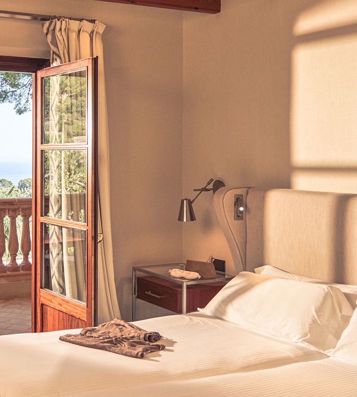 Guest room with French doors open to a private balcony overlooking the sea