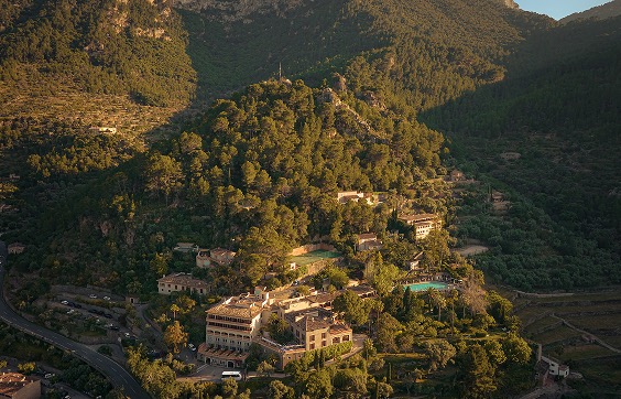 Aerial view of the hotel complex and pool terraced into the pine-covered hillside above Deià