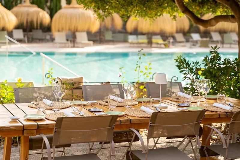 Poolside table set for dining in the shade of a tree at the hotel's Sa Figuera restaurant