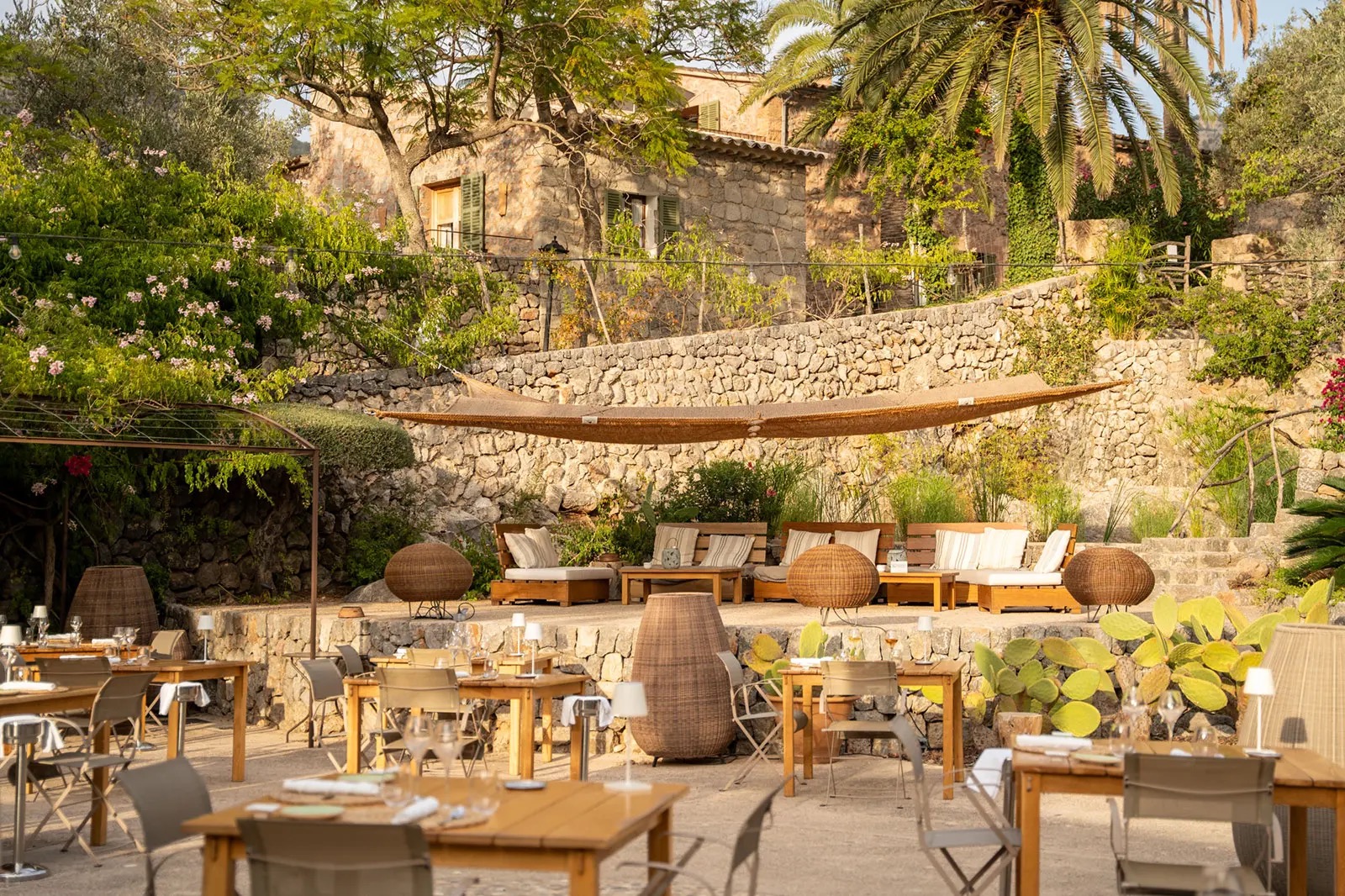 Outdoor terrace lounge with wicker sofas, a hammock and the stone finca building behind