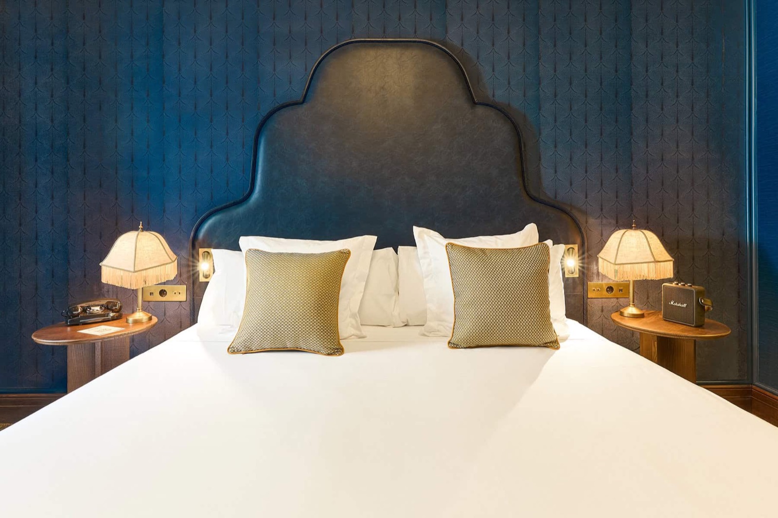 Deluxe room with a dark blue leather headboard and patterned wallpaper