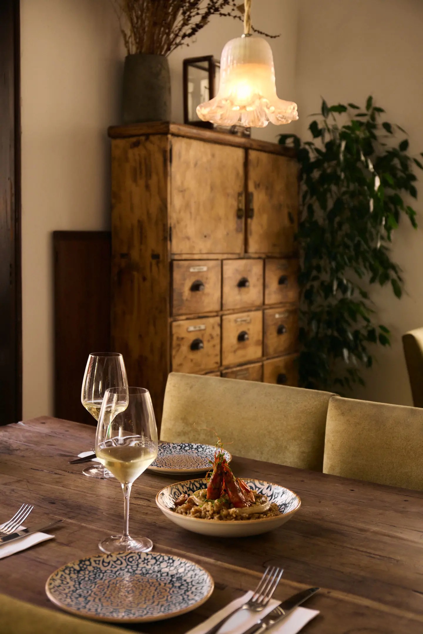 Table set with a shrimp and rice dish and glasses of white wine in the restaurant's dining room