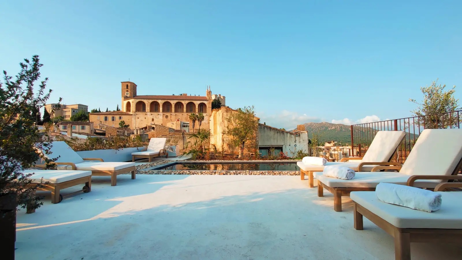 Rooftop terrace with sun loungers and a small plunge pool overlooking Arta's old town and the parish church tower