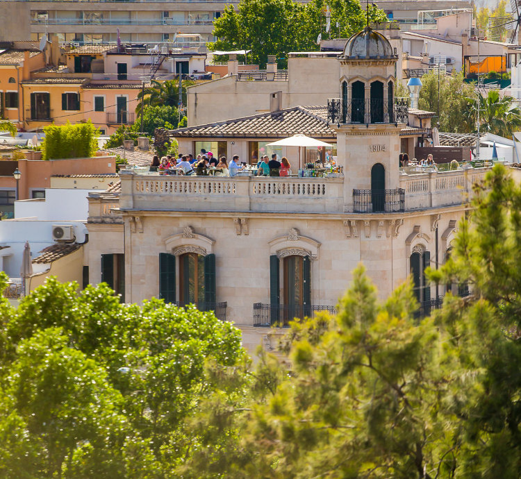 The hotel's modernist corner facade and rooftop terrace seen from a distance, with its domed tower rising above Santa Catalina's rooftops