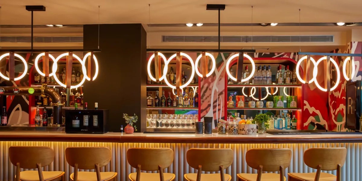Hotel bar with illuminated ring pendant lights and a stocked back bar