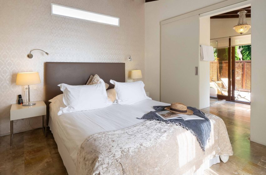 Guest room with a dark leather headboard and sliding door opening onto a private terrace
