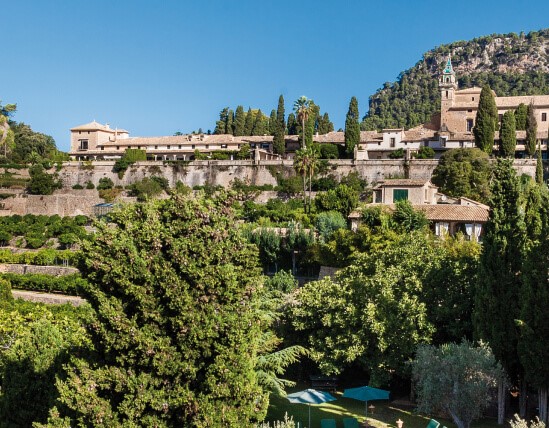 View over the hotel's pool and gardens up to Valldemossa's Carthusian monastery on the hill