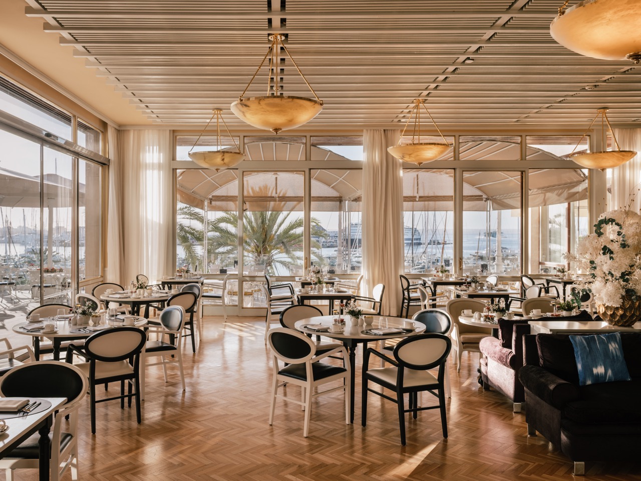 Restaurant dining room with round tables and floor to ceiling windows over the marina