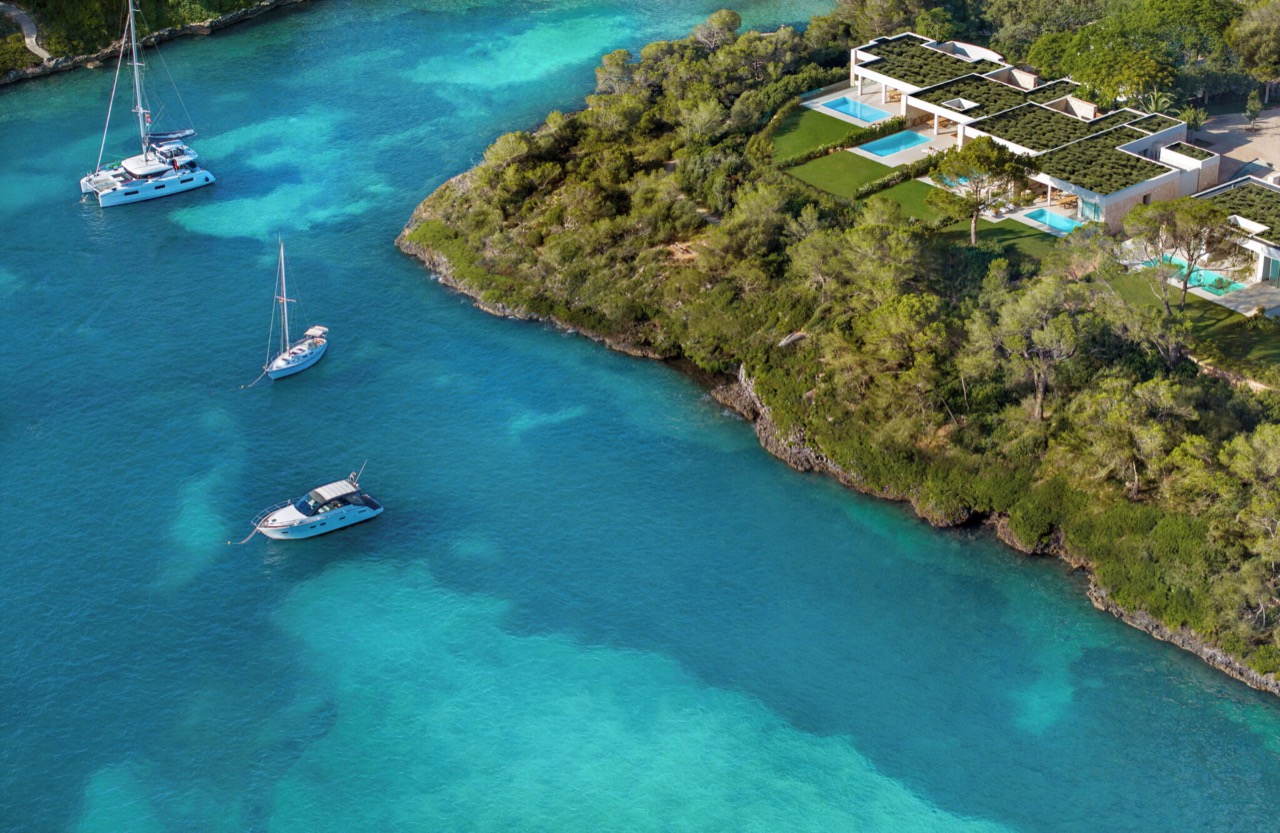 Aerial view of the resort's villas and pools over a turquoise cove