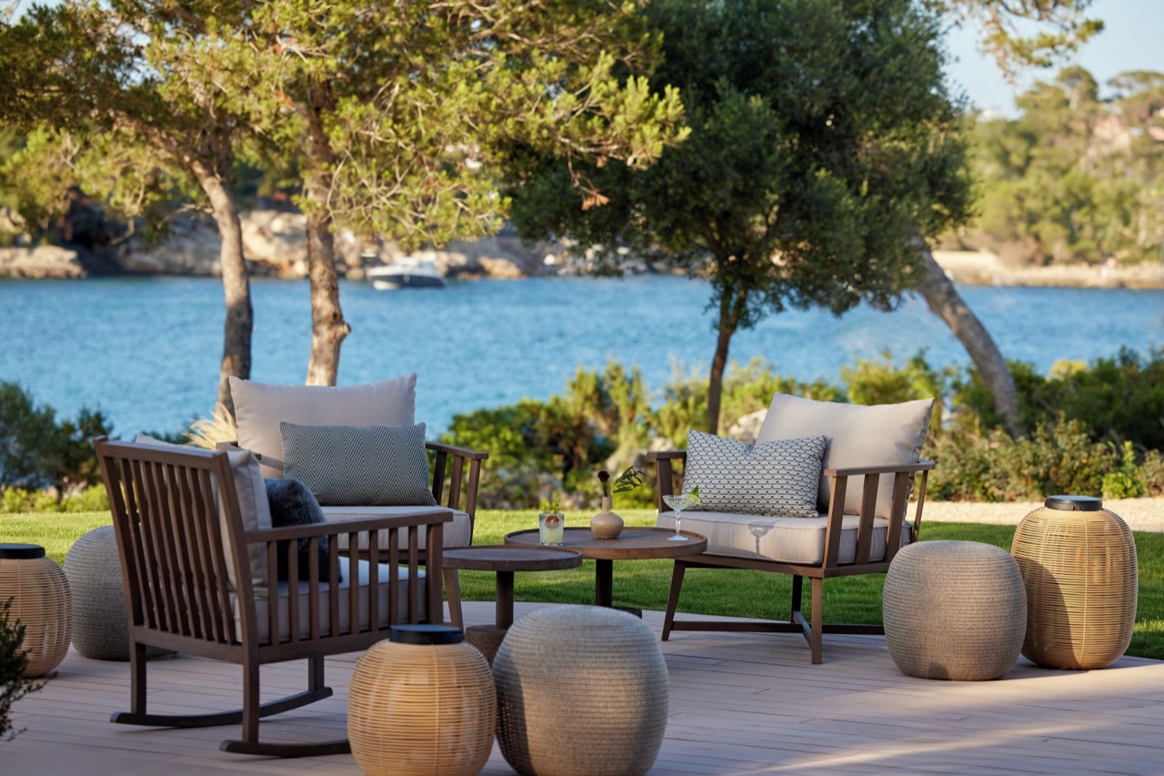 Lounge seating on a terrace among pine trees facing the water
