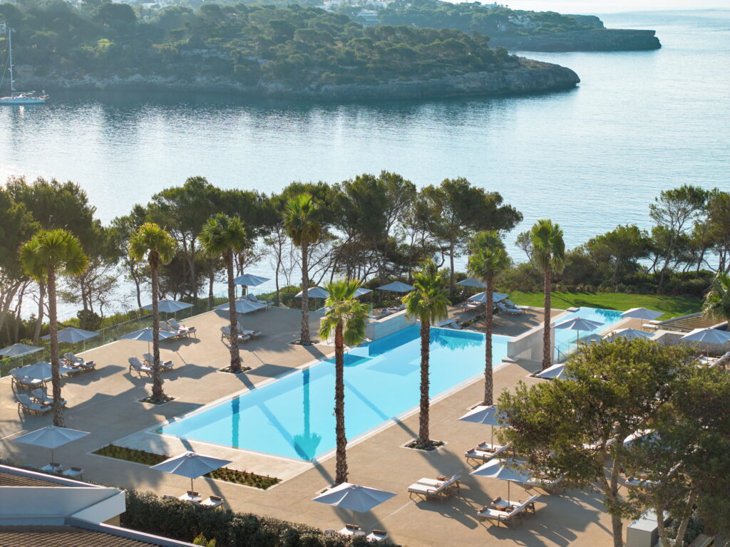 Main pool lined with palm trees overlooking the bay