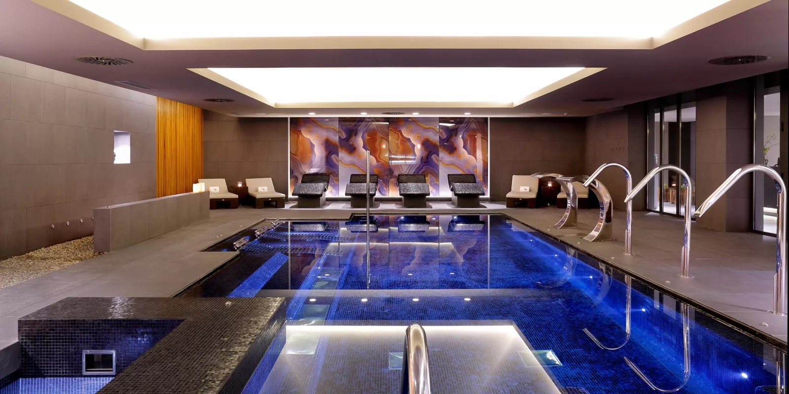 Indoor spa pool with loungers and an onyx feature wall