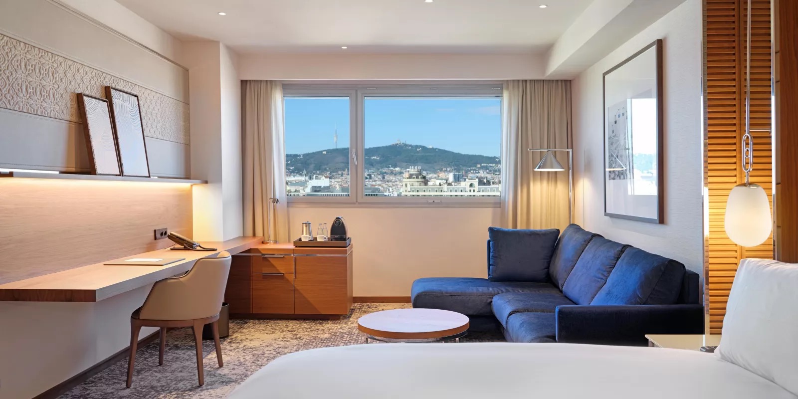 Suite living area with a blue sofa and a Barcelona skyline view