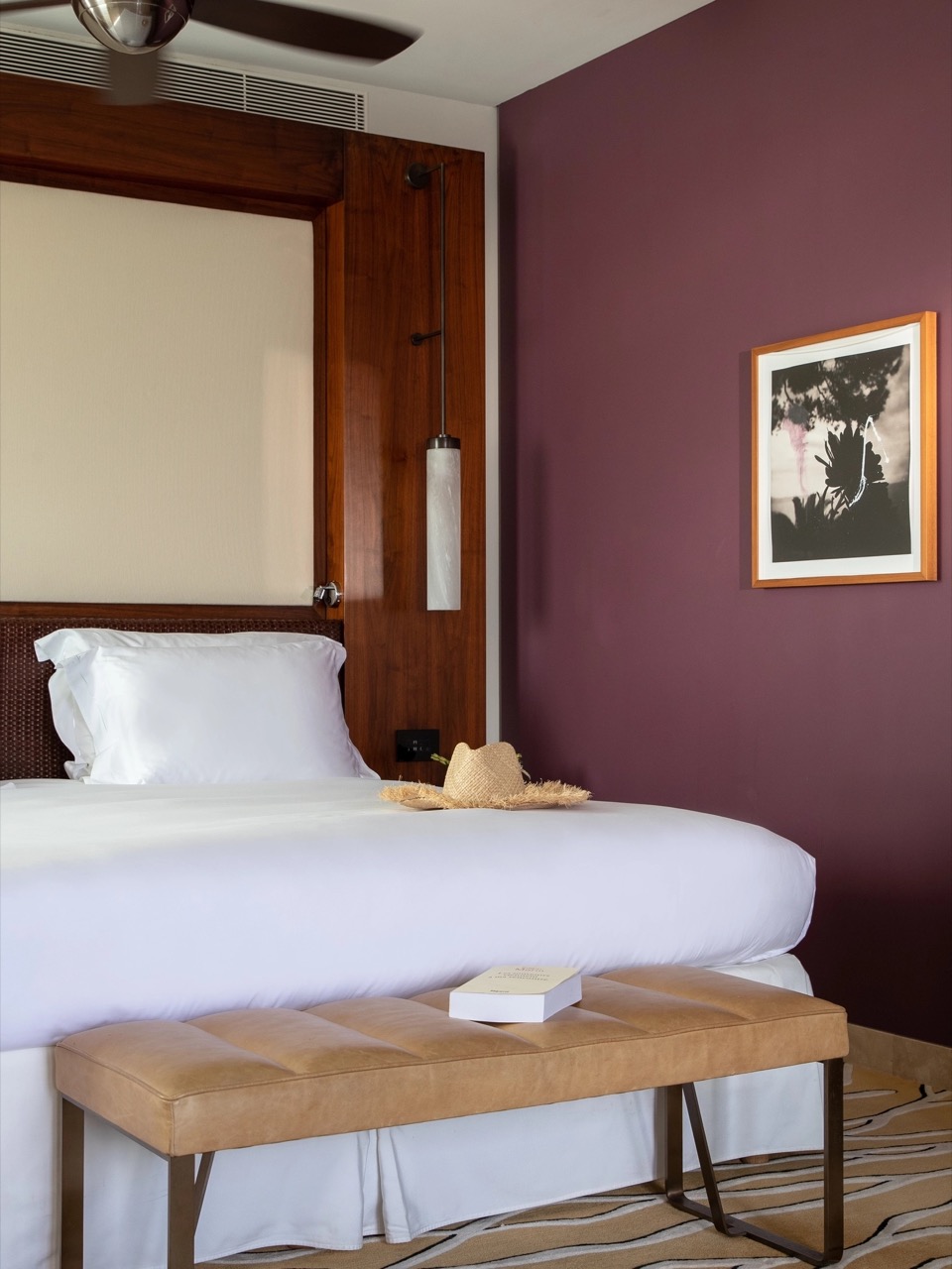 Hotel bedroom with a dark wood headboard and burgundy accent wall