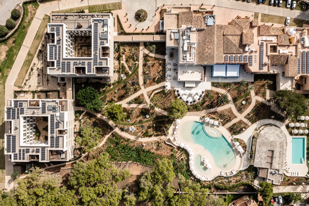 Aerial view of Kimpton Aysla Mallorca showing the hotel buildings, gardens and curved swimming pool
