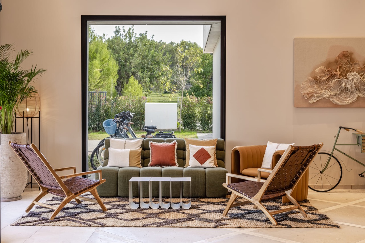 Common area lounge at Kimpton Aysla Mallorca with a green sofa and leather chairs facing a garden view