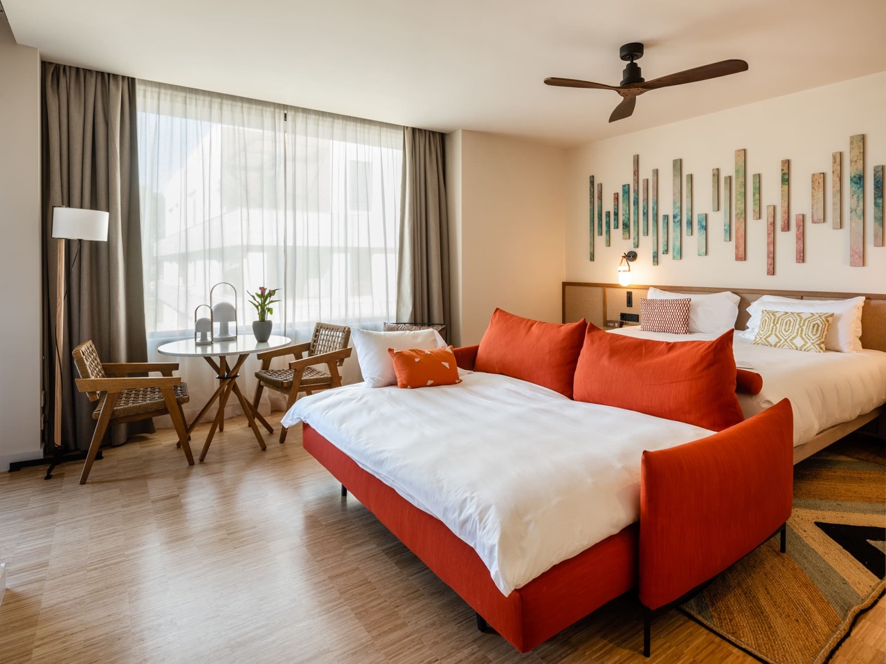 Premium room at Kimpton Aysla Mallorca with an orange daybed sofa and a colorful ceramic wall installation above the bed