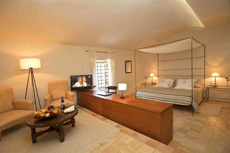 Suite with a four-poster canopy bed, striped bedding and a sitting area with armchairs