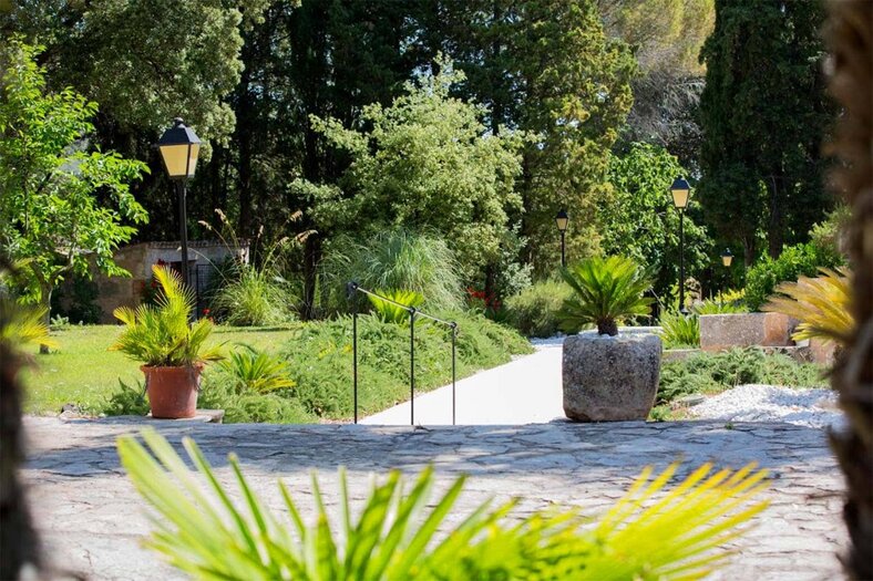 Stone garden path lined with lanterns and potted palms leading through the grounds