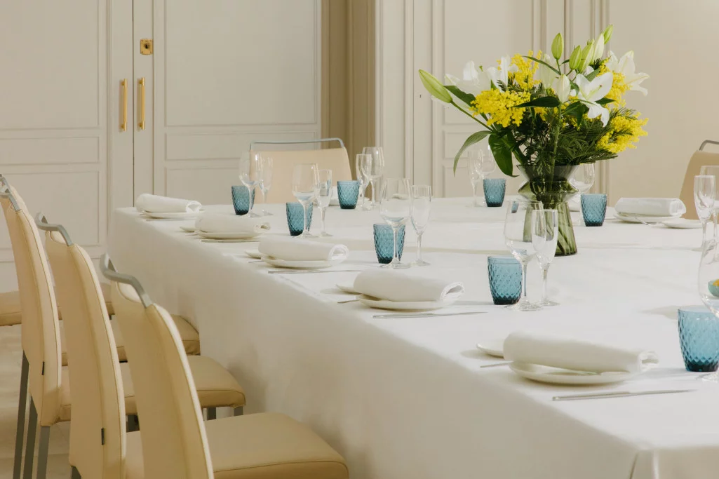 Private dining table set with white linens, wine glasses and a flower centrepiece