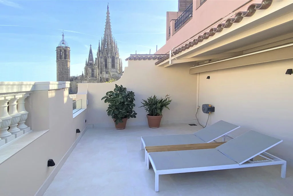 Private rooftop terrace with sun loungers, potted plants and a cathedral view