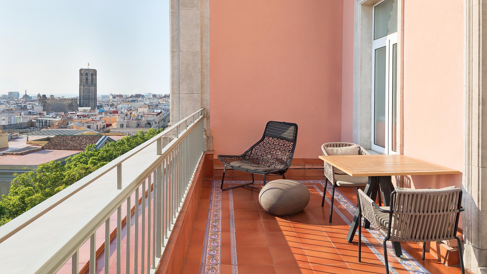 Rooftop terrace with lounge seating and a view toward the Boqueria bell tower