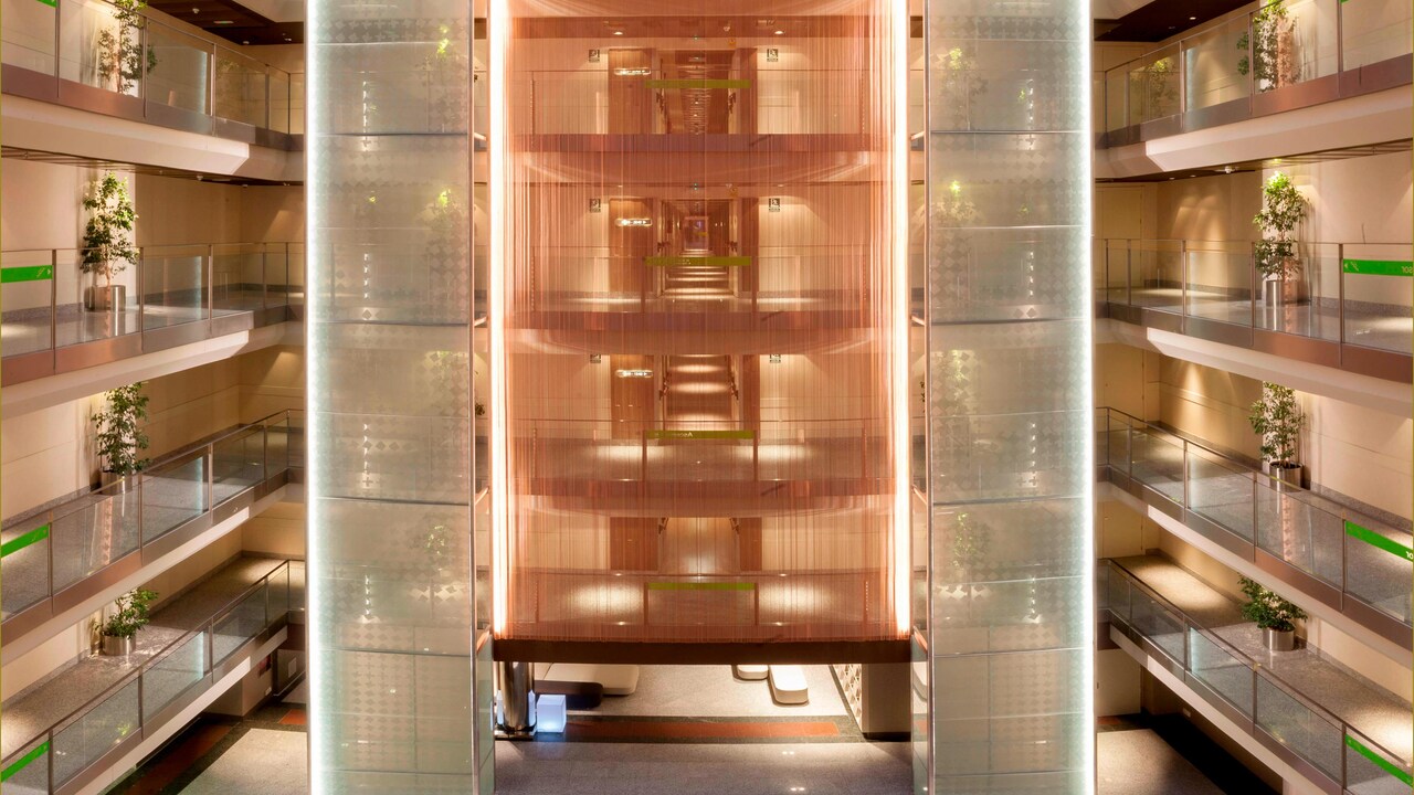 A multi-storey atrium inside the hotel with open corridors on each floor and a lit central shaft running up through the building.