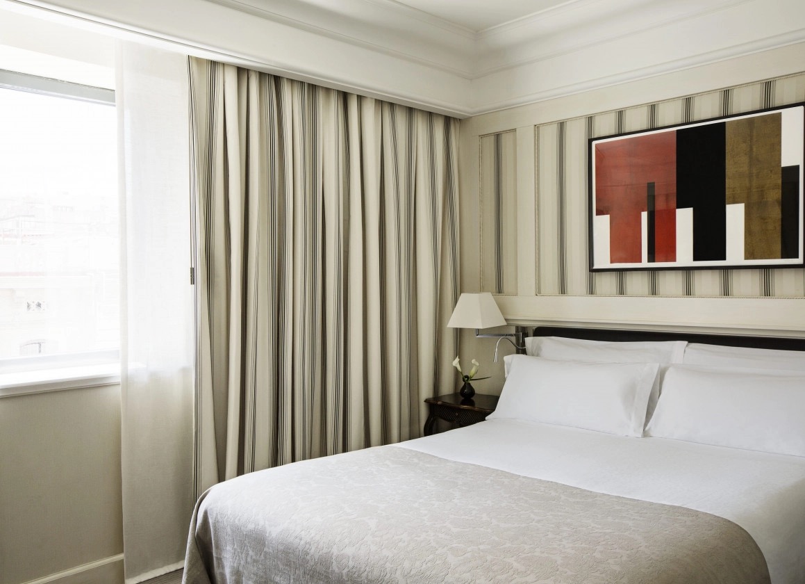 Deluxe room with striped curtains, abstract artwork and white bedding