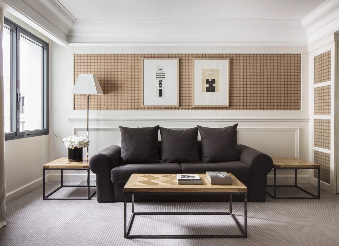 Junior suite living area with a dark sofa, checked wall panel and framed prints
