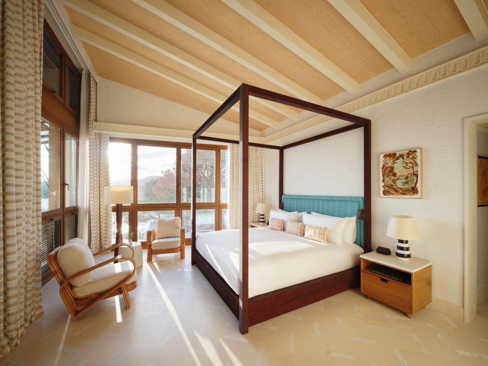 Guest room at Mandarin Oriental Punta Negra with a four-poster bed and teal headboard beneath a striped vaulted ceiling, facing sea-view windows