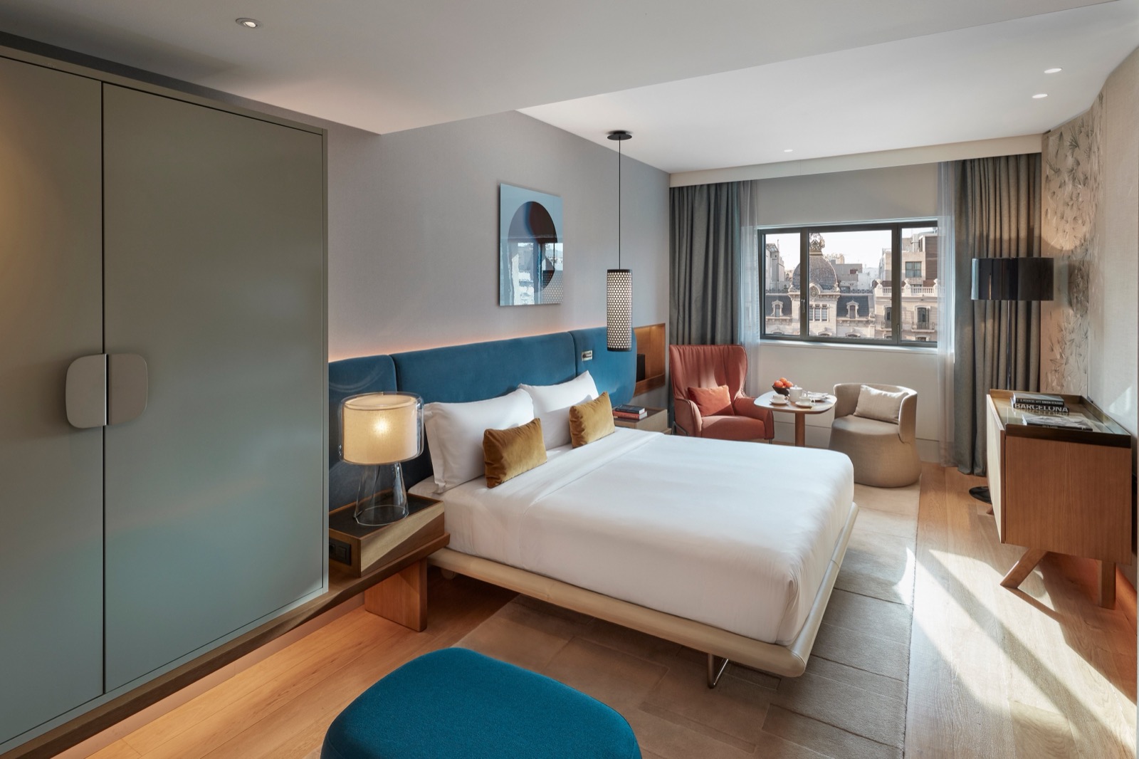 Deluxe Boulevard Room with a blue upholstered headboard and a city-view window