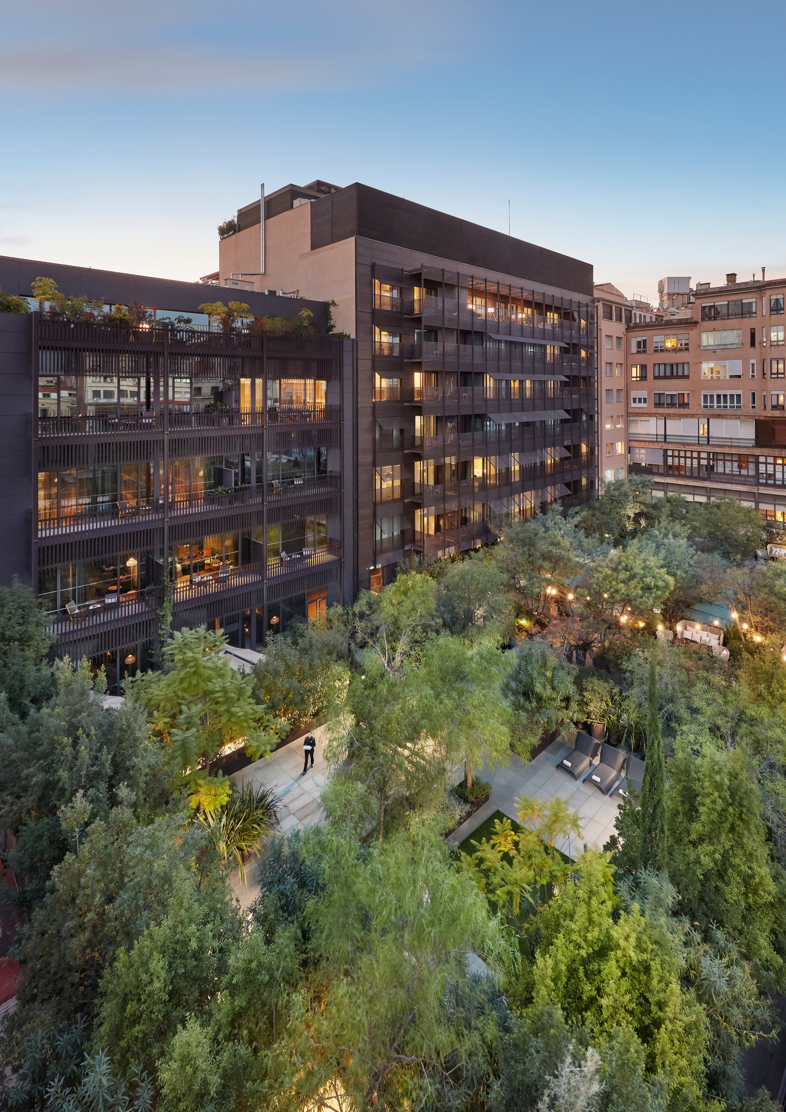 The Mimosa Garden courtyard terrace at dusk, set among trees behind the hotel