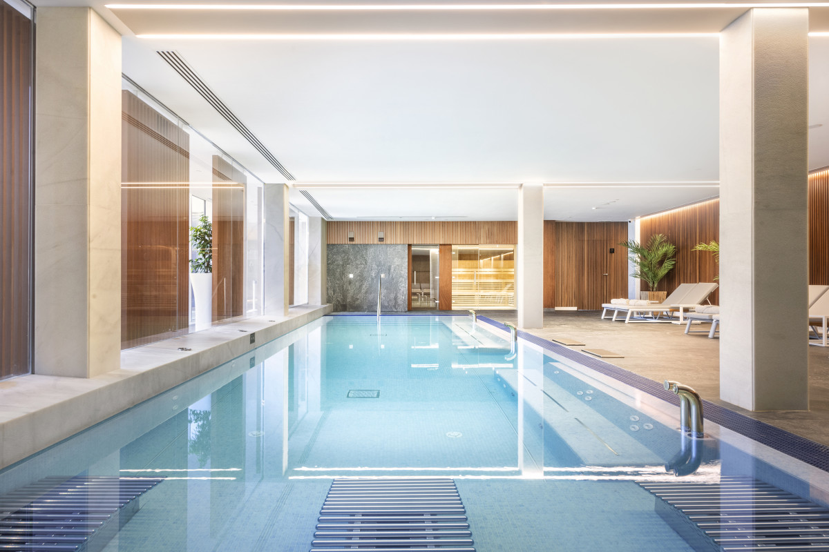 Indoor spa lap pool with wood-paneled walls and a sauna behind