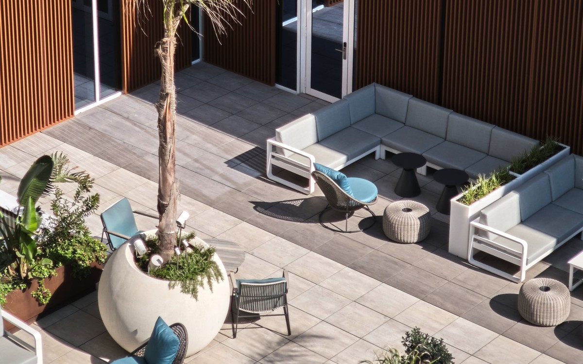 Rooftop terrace lounge with sectional seating and a potted palm