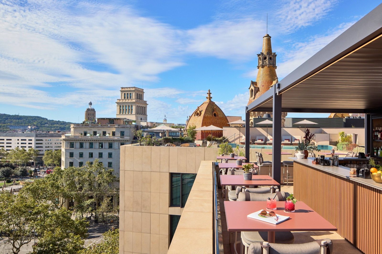 Rooftop bar terrace with pink dining tables and a view of the city's domes