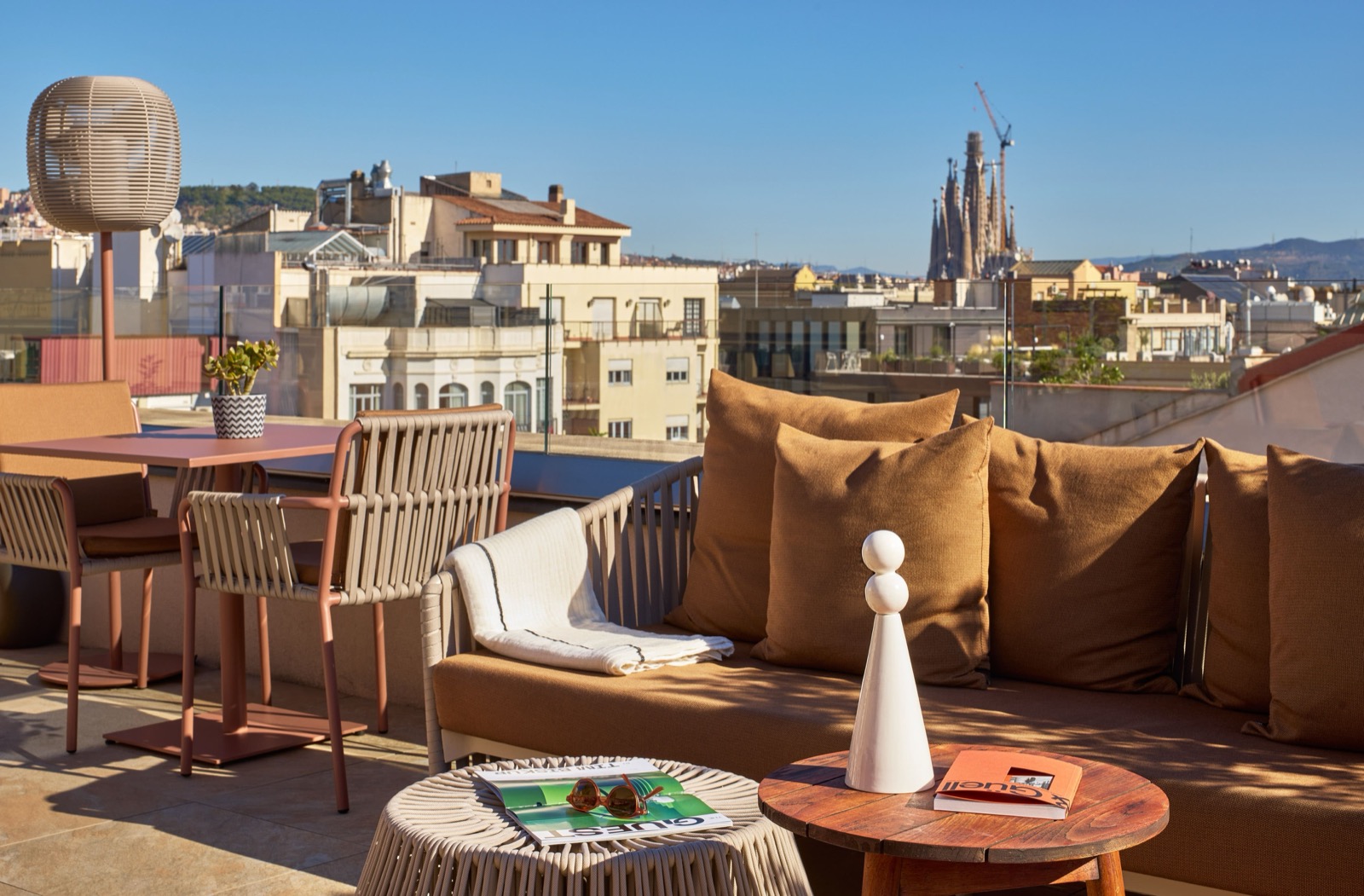 Rooftop lounge terrace with sofas and a distant view of the Sagrada Família