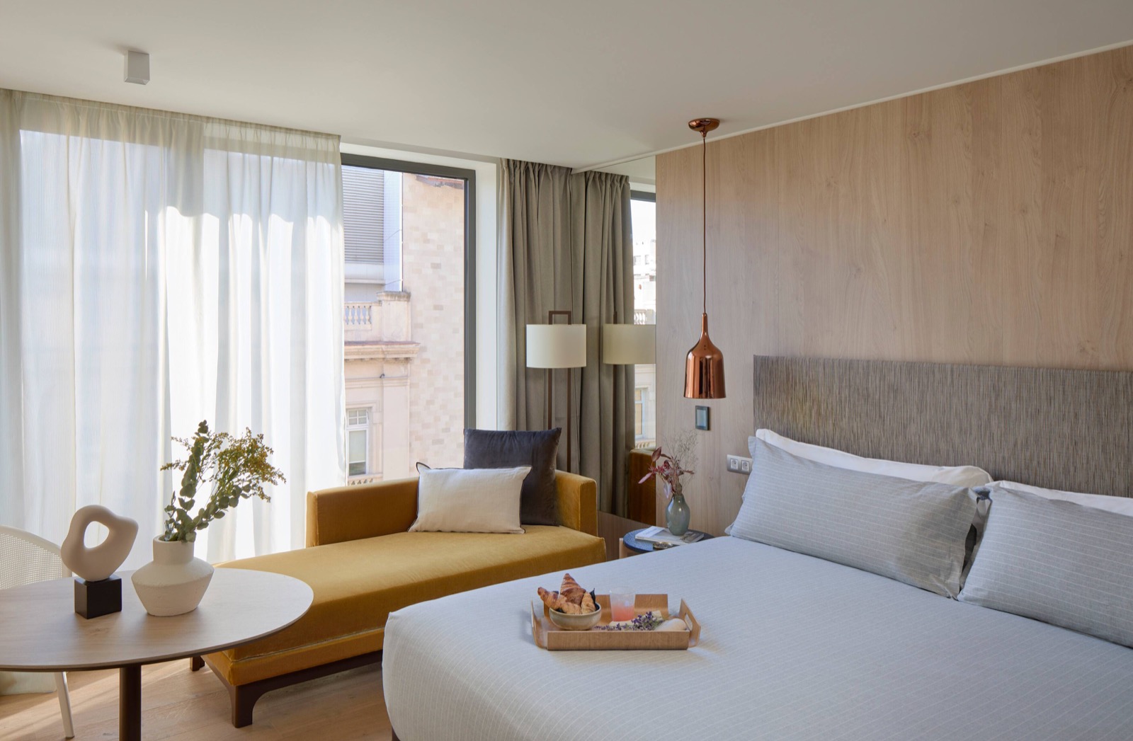Guest room with a breakfast tray, a mustard velvet daybed and sheer curtains