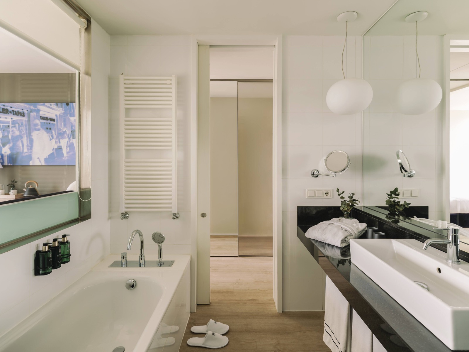 Bathroom with a tub, an in-mirror TV and Barcelona street photography