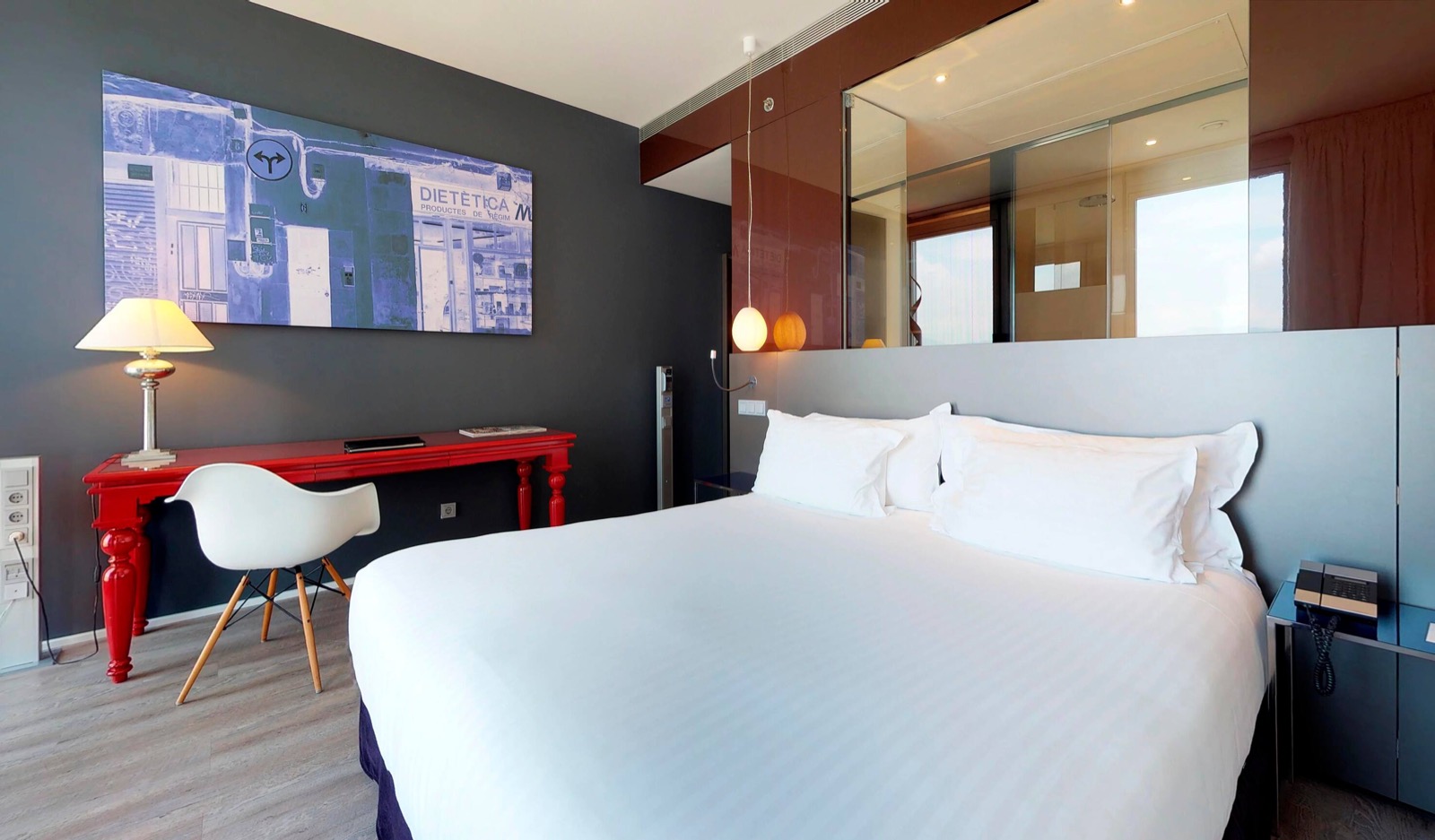 Guest room with a red desk and a window over Barcelona
