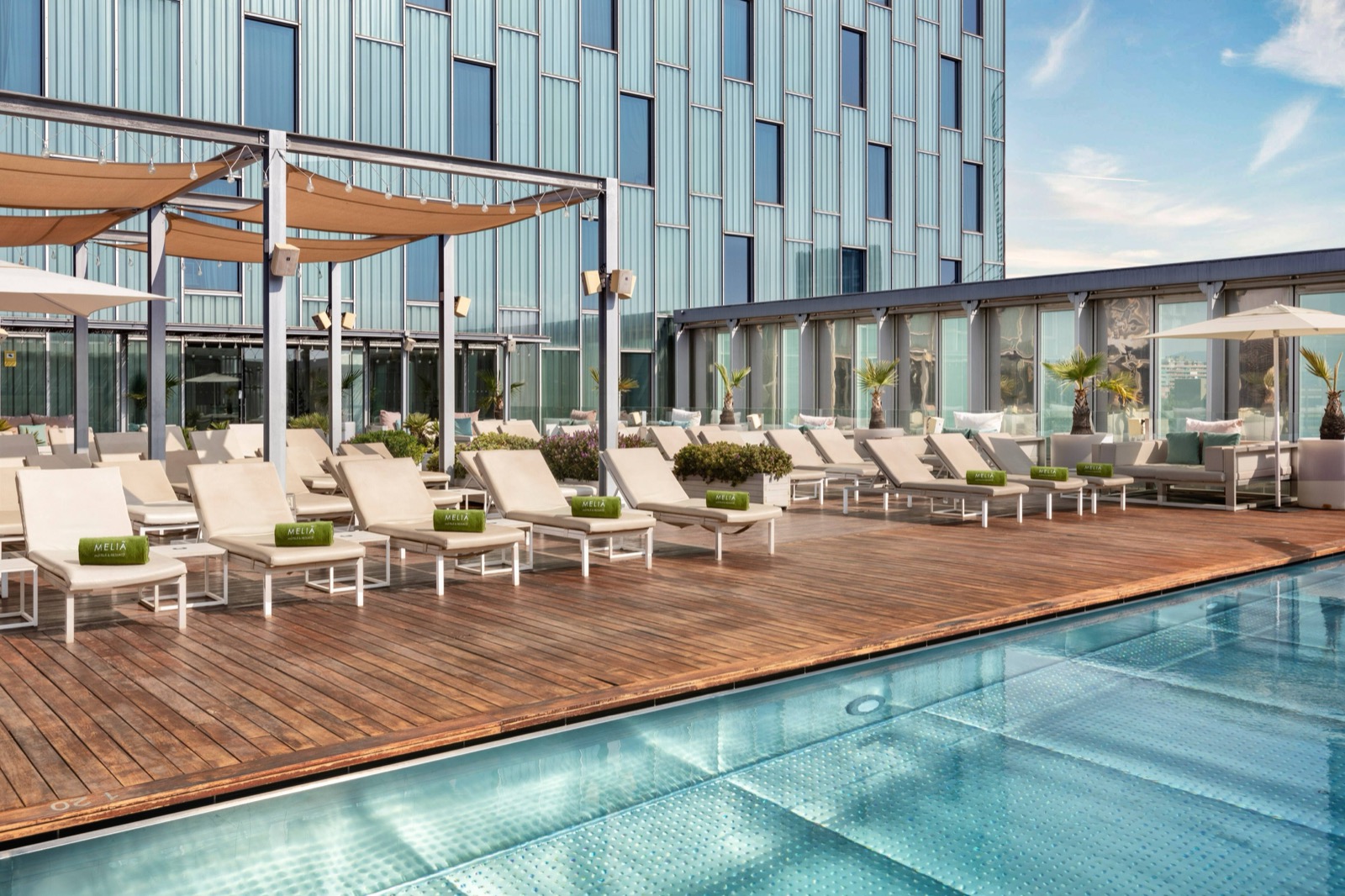 Rooftop pool and terrace with lounge chairs against the Sky tower facade
