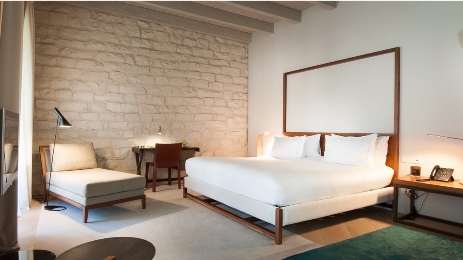 Junior suite with a four-poster wood bed against an original stone wall