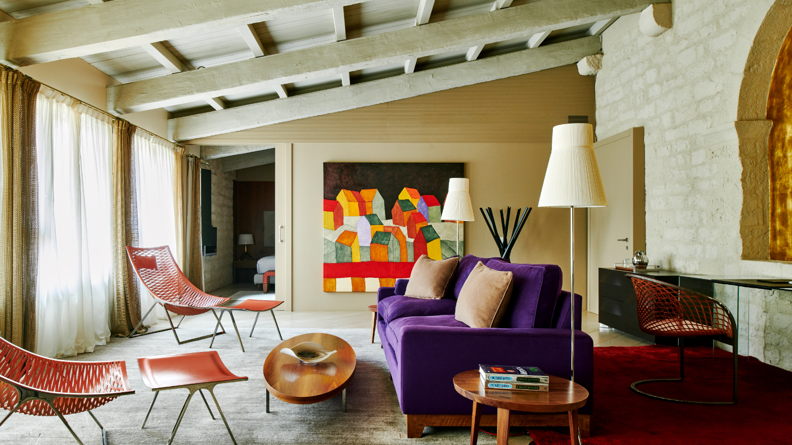 Mercer Barcelona suite living area with stone walls, exposed beams and a purple sofa