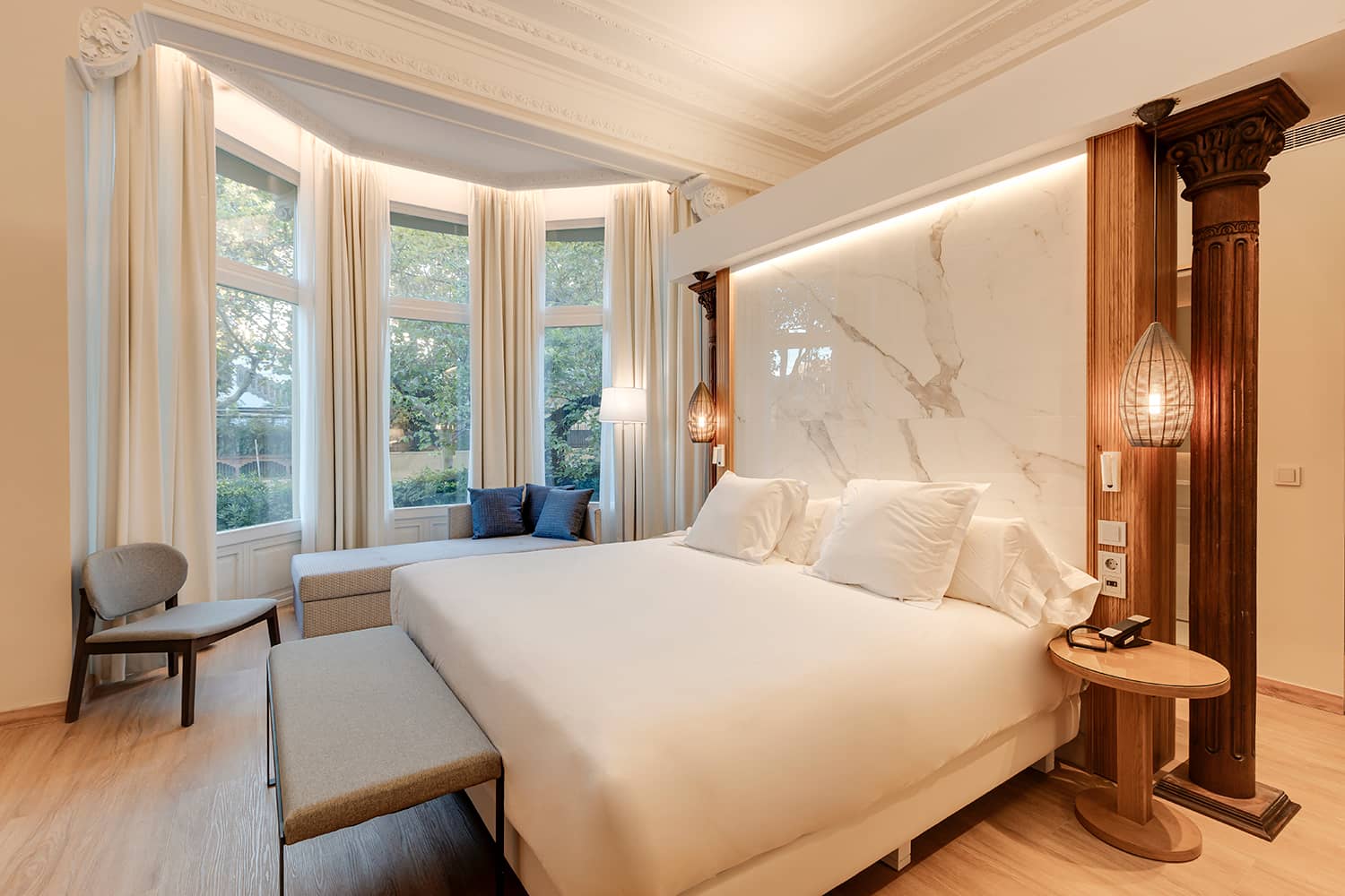 Suite bedroom with a bay window, an ornate column and a marble headboard