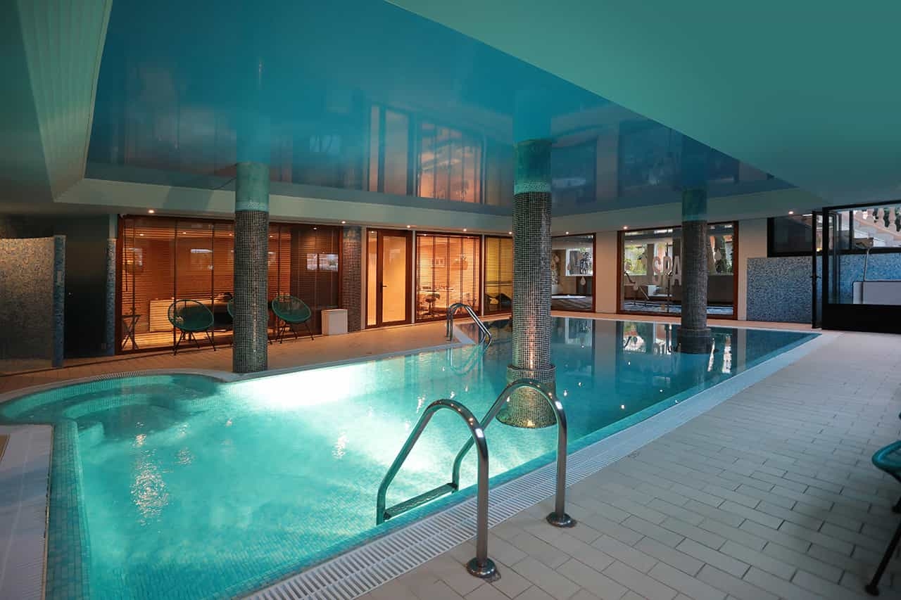 Indoor thermal pool in the Blue Sensations Spa, lined with mosaic-tiled columns and glass-walled treatment rooms