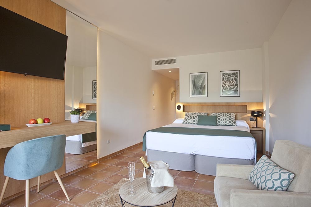 Guest room with a king bed, terracotta tile floor and a mirrored sliding-door wardrobe wall